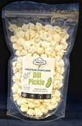 Packaged dill pickle popcorn with a label on a dark background