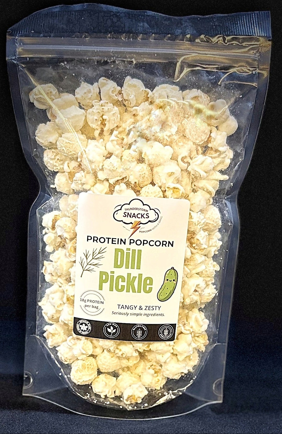 Packaged dill pickle popcorn with a label on a dark background
